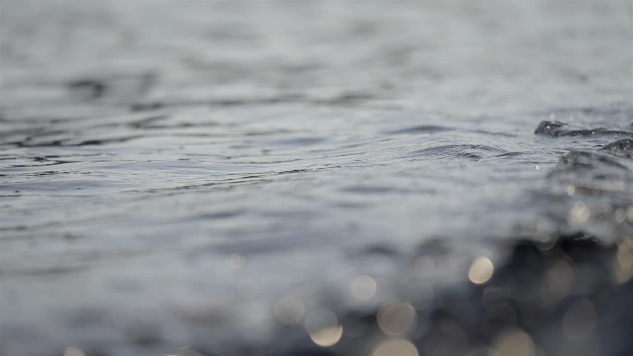 Close-Up of Dark Polished Pebbles on Jasper Beach with Ocean Wave