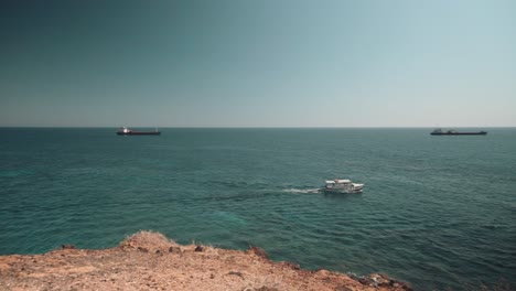 clip of a small ferry with tourists sailing along a beautiful beach on a greek island