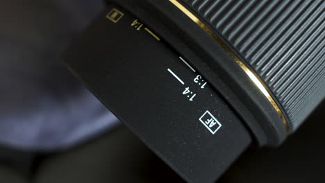 un primer plano de una lente de cámara dslr de apertura fija, el anillo de enfoque gira mientras retrae el núcleo de la lente que está marcado con una escala de distancia y se utiliza como ayuda para enfocar al sujeto