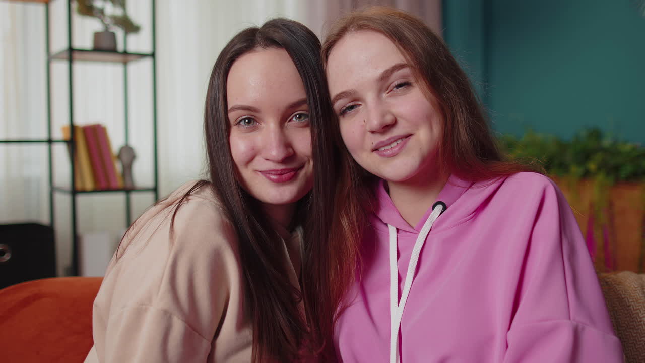 Крупный план портрета счастливых, привлекательных девушек-подруг, сестер, которые обнимаются, улыбаются и смотрят в камеру
