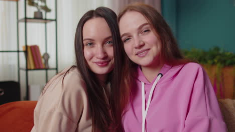 Close-up-portrait-of-happy-attractive-girls-friends-siblings-embracing,-smiling,-looking-at-camera