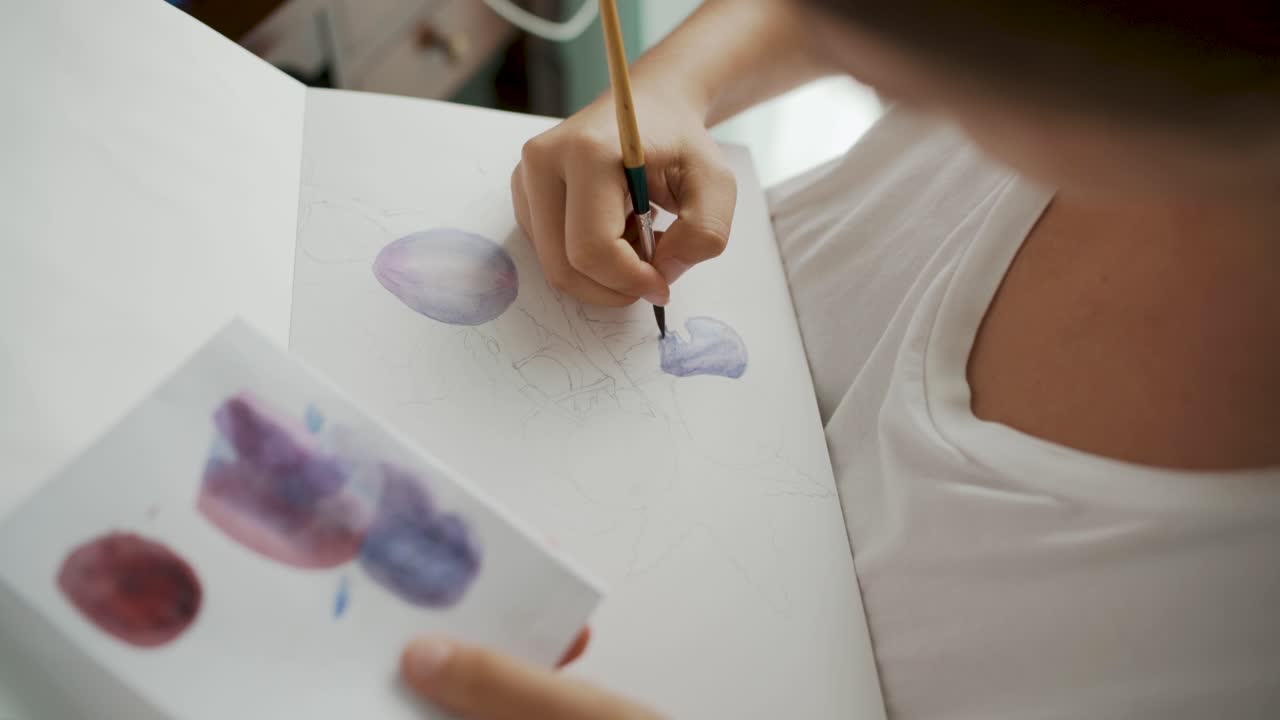 fotografía de cerca de una mujer joven dibujando en papel con acuarela