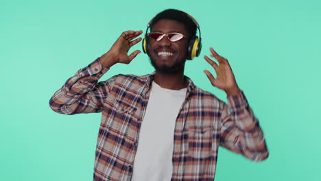 cheerful attractive man listening music via headphones and dancing disco fooling around having fun