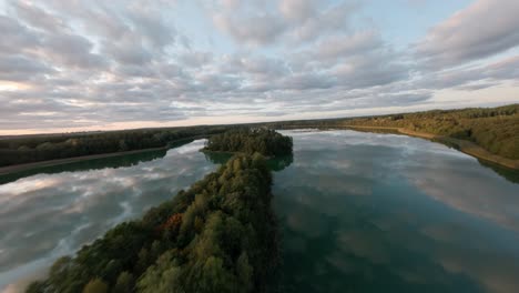 fpv drone glides over autumn-clad sawinda lake, masuria, poland.