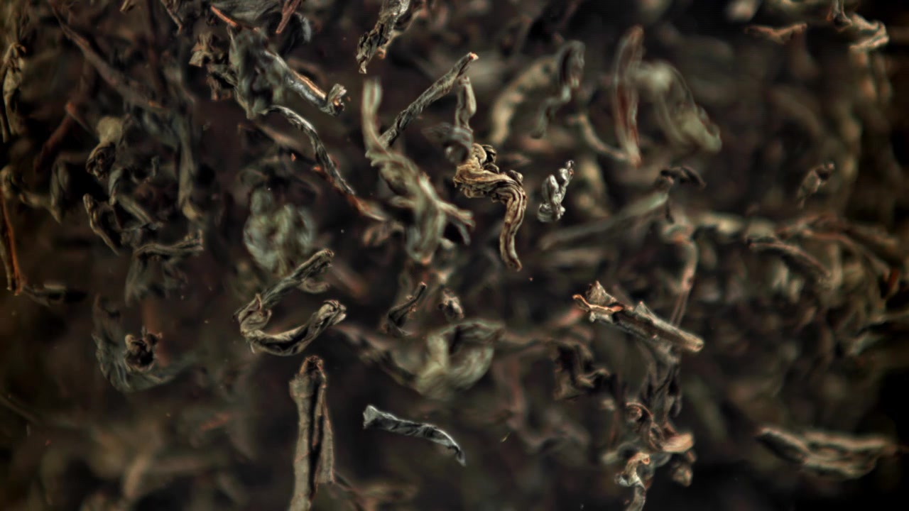 Close-up of Dried Tea Leaves Falling and Floating in Water