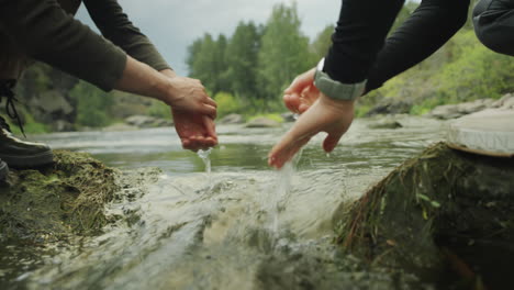 female hikers washing hands with water from river