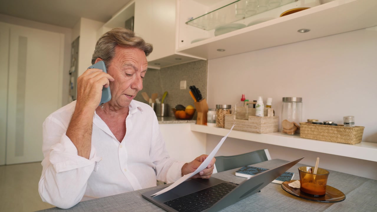 Uomo maturo che lavora da casa mentre parla al telefono