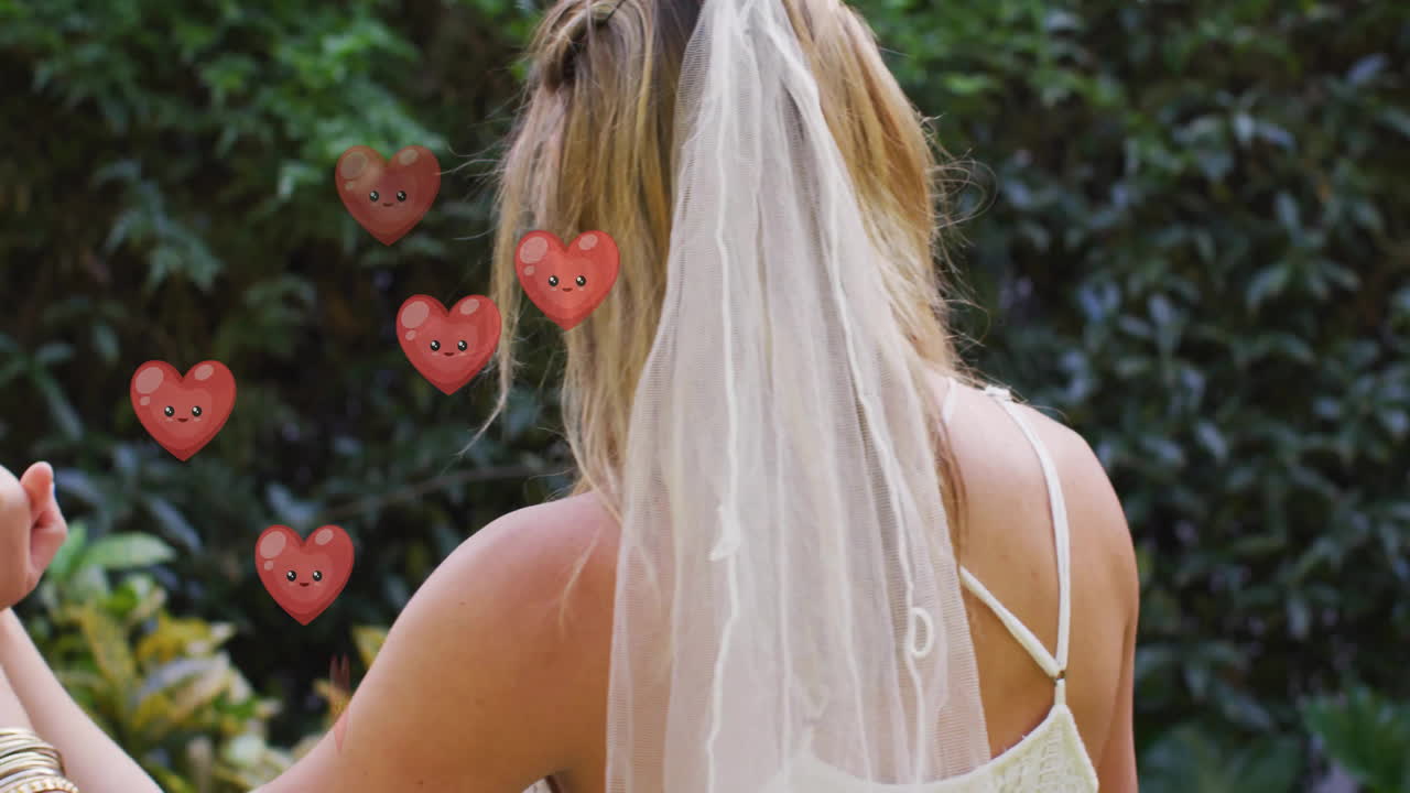 Animation of hearts floating over diverse female married couple dancing