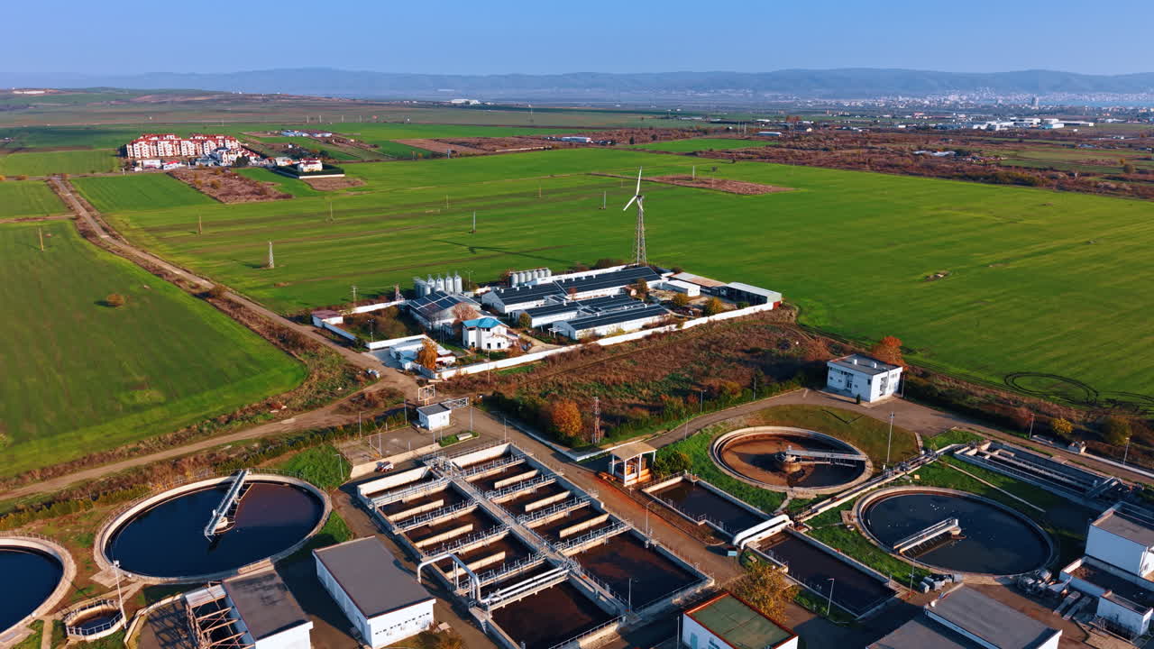 Flight over the water treatment plant with numerous reservoirs. Approaching the warehouses with solar panels on the roofs