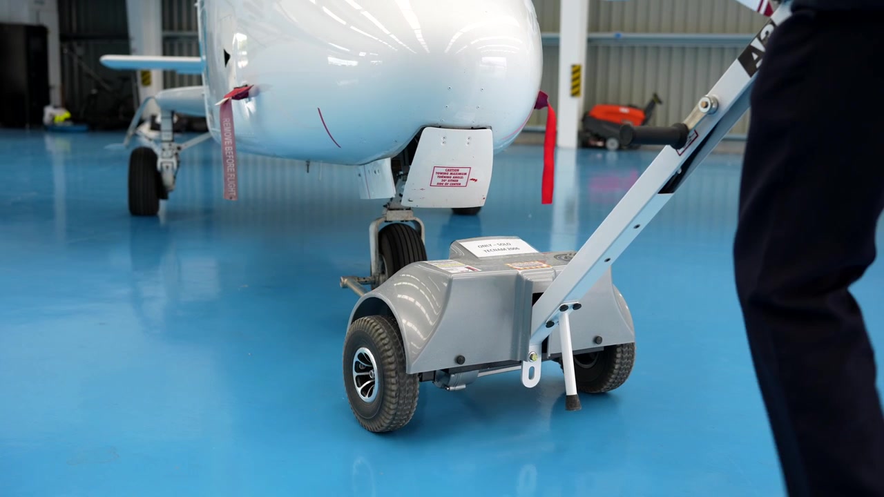 Electric Tow Tug Moving Small Airplane in Hangar