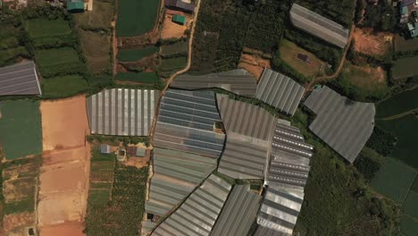 top down drone shot of agricultural land featuring greenhouses and a village outside dalat in the central highlands of vietnam on a sunny day