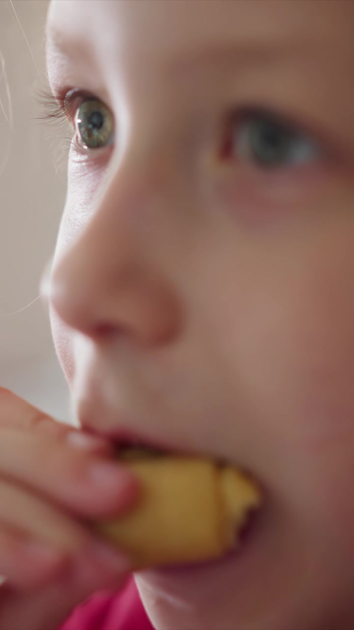 Close up of young girl eating various foods including banana apple slice and sandwich. Her facial expressions change as girl tastes each item while holding them in her hand. Soft lighting