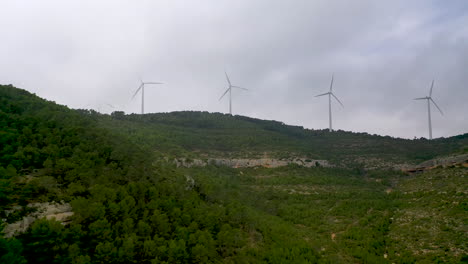 Drohnen-Push-In-Schuss-Auf-Sich-Drehende-Windkraftanlagen-Auf-Bergrücken-In-Nebel