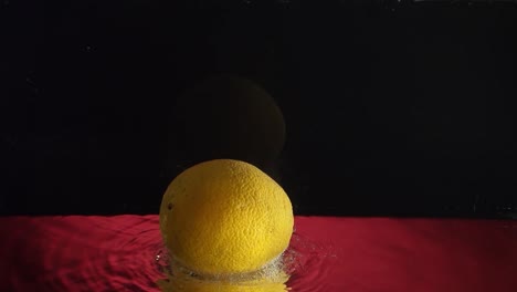lemon under water whith bubbles in slowmotion lemon under water whith bubbles over redblack background in slowmotion