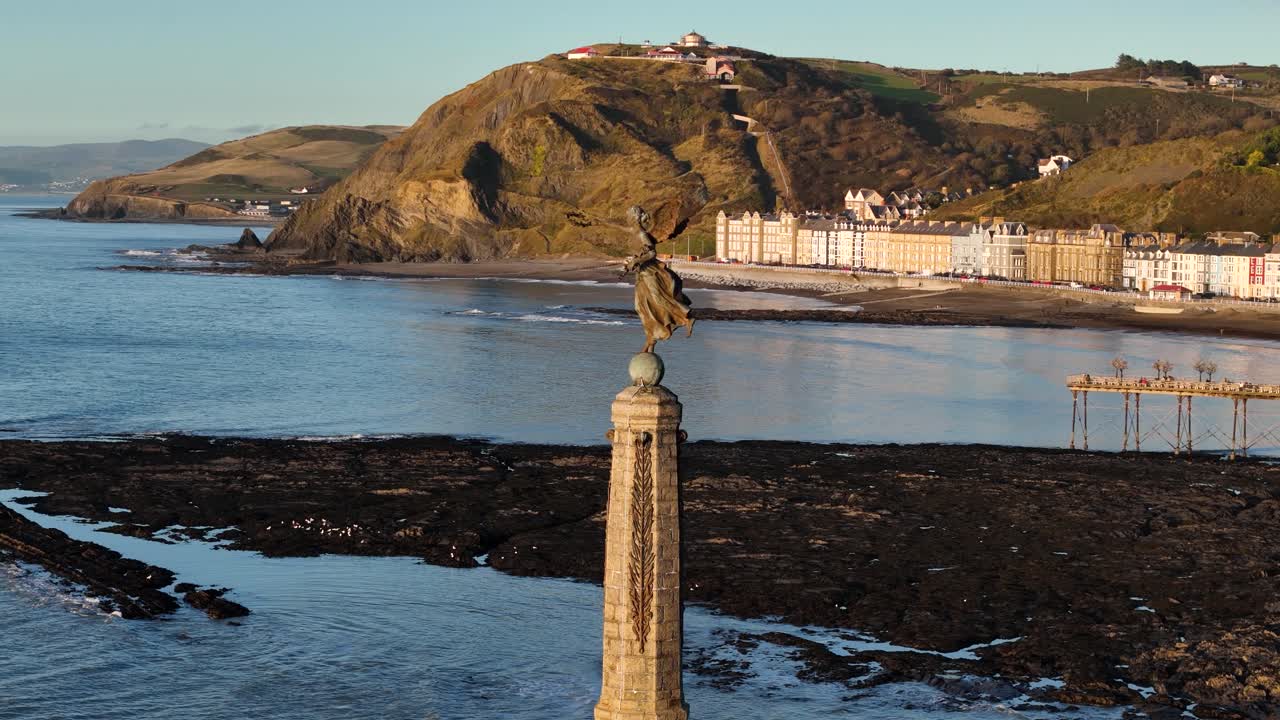 Stunning drone footage of Aberystwyth Castle's Angel monument at sunset, capturing its historic ruins, scenic coastline, and golden hour beauty on a peaceful summer evening.