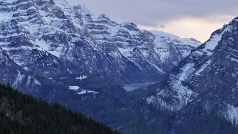 Panning-drone-clip-of-mountains-covered-in-snow,-in-early-morning