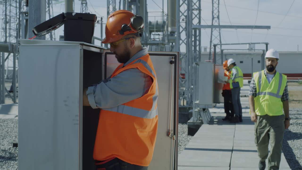 Electrical Workers Inspecting Equipment at a Power Station