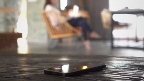 missed phone call on smartphone with a woman working at the background in home setting