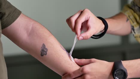 maestro de tatuaje de cultivo transfiriendo la imagen del tatuaje en el brazo del cliente