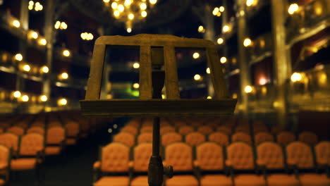 empty theater with a music stand and softly lit ornate decor