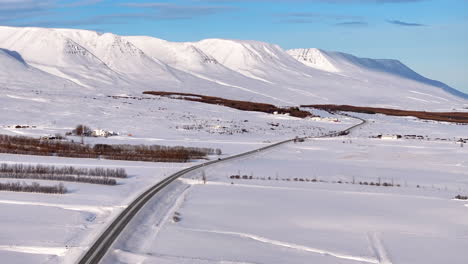 Luftaufnahme-Des-LKW-Verkehrs-Auf-Der-Straße-Zwischen-Schneebedeckten-Bergen-In-Island