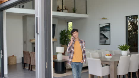 talking on smartphone, teenage boy standing in modern living room, smiling