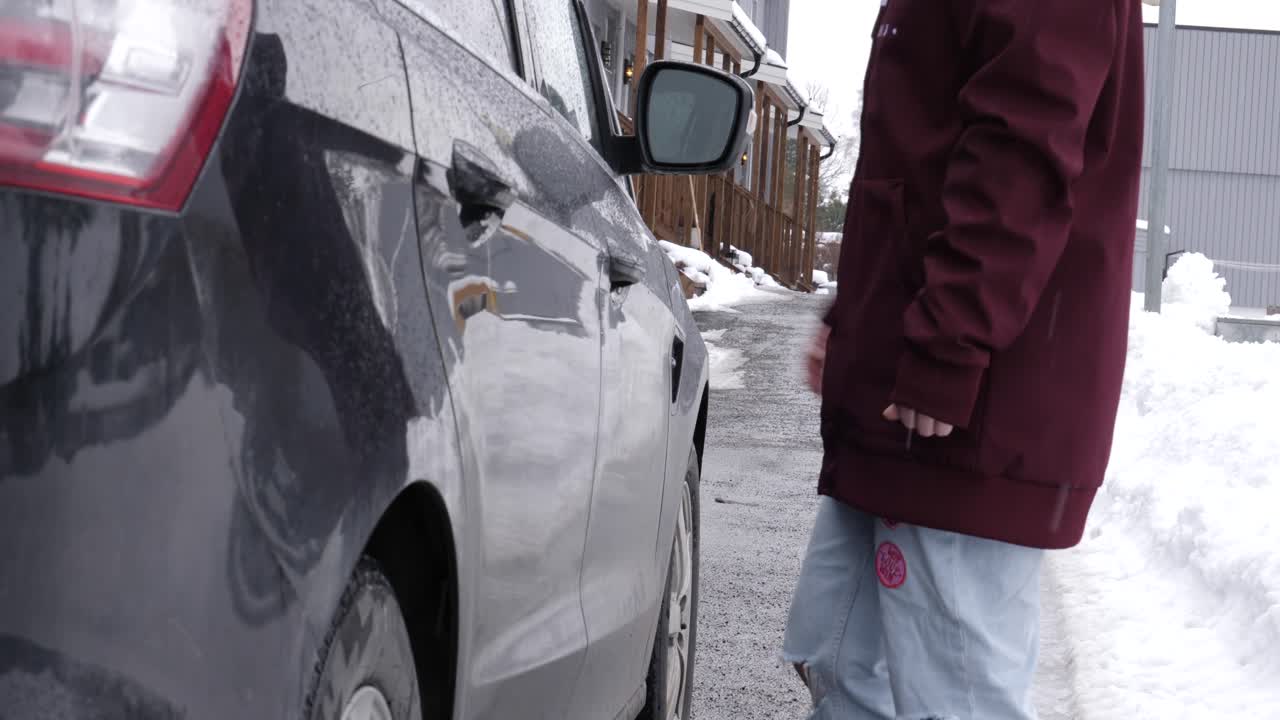 woman closing right car door on black car, no face
