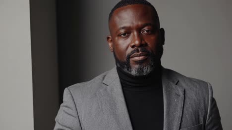 professional businessman standing confidently in gray jacket, black turtleneck, projecting corporate success within sleek, minimalist environment