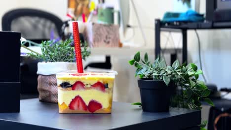bright fruit dessert with red sparkler on a cozy office desk with green plants, ideal for lifestyle, celebrations, and food promotions