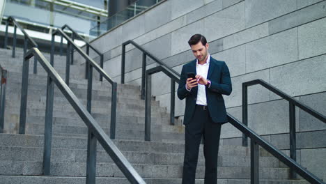 Man-using-phone-at-modern-street.-Businessman-checking-time-on-twatch-outside