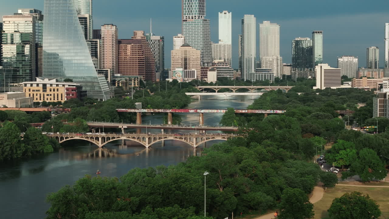 Drone captures Downtown Austin skyline glowing in the evening light with Ladybird Lake reflecting the warm cityscape. A calm, cinematic moment as day transitions into night across the water