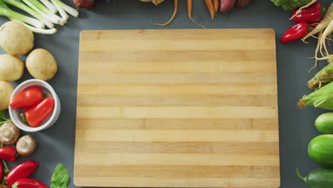 video of fresh fruit and vegetables and wooden chopping board with copy space on grey background