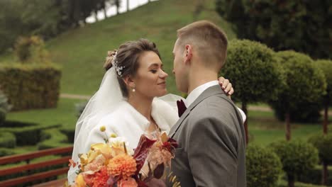 Lovely-newlyweds-caucasian-bride-embracing-groom-in-park-making-kiss,-wedding-couple-family-hugging