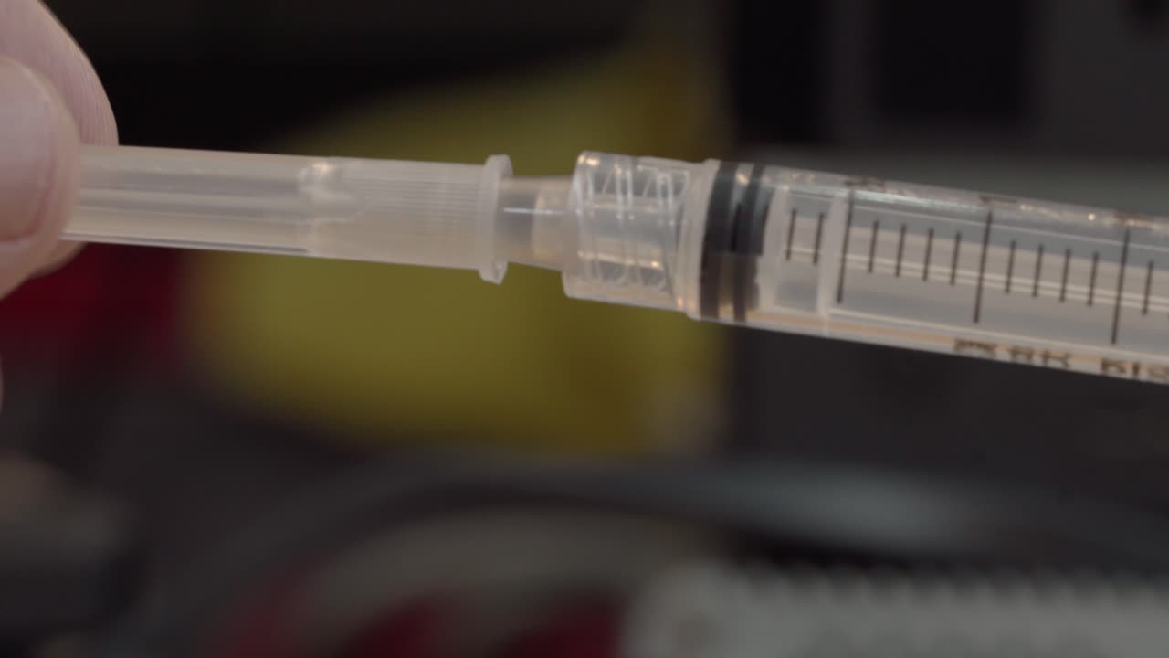 Close-up of hands assembling a syringe under soft indoor light, cinematic shallow depth of field