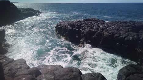 gimbal amplia panorámica de agua de mar derramándose en un estanque de marea entre las antiguas rocas de lava cerca del baño de la reina en la isla hawaiana de kaua'i