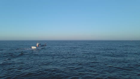 toma aérea, barco de pesca navega a través de pequeñas olas en mar abierto cerca de playa penón del cura frente a la costa de españa contra un cielo azul claro- mar mediterráneo