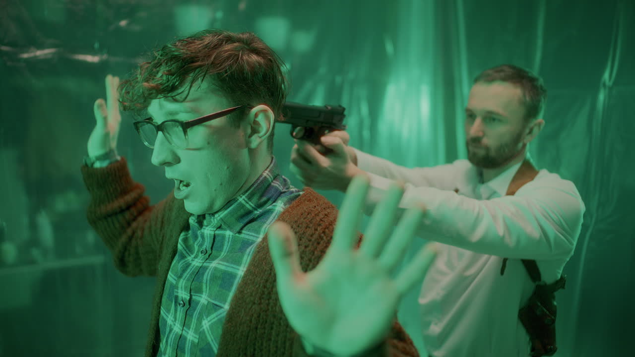 злой убийца поворачивается с поднятыми руками, под прицелом детектива