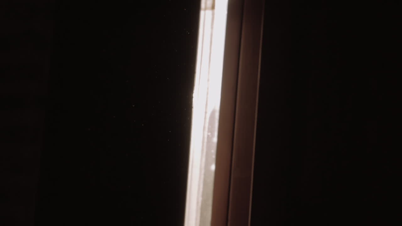 el sol de la mañana en la grieta del obturador y las partículas de polvo voladoras