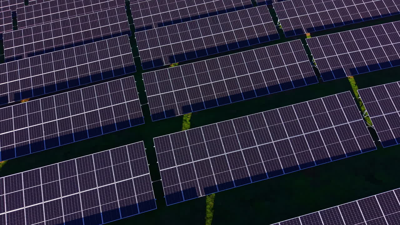 Un vasto impianto fotovoltaico assorbe la luce solare su un paesaggio verde, a testimonianza degli avanzamenti dell'energia rinnovabile nella tecnologia moderna.