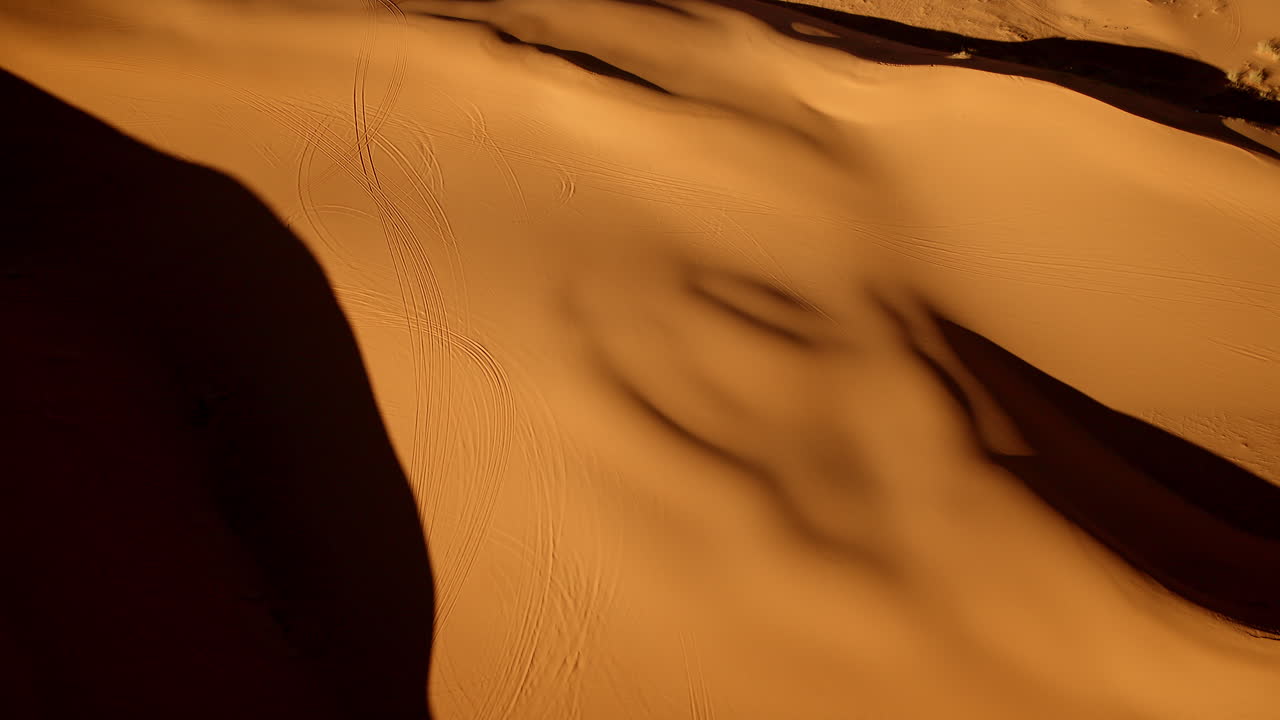 Ethereal aerial footage unveils the elegant curves and striking colors of the pink sand dunes below.