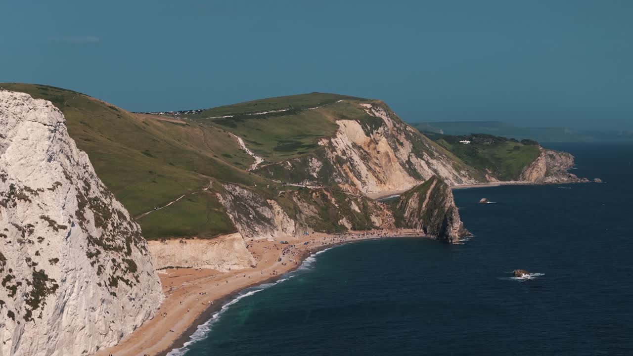 Stoupající letecký záběr s posunem dolů na Durdle Door a tyčící se útes.