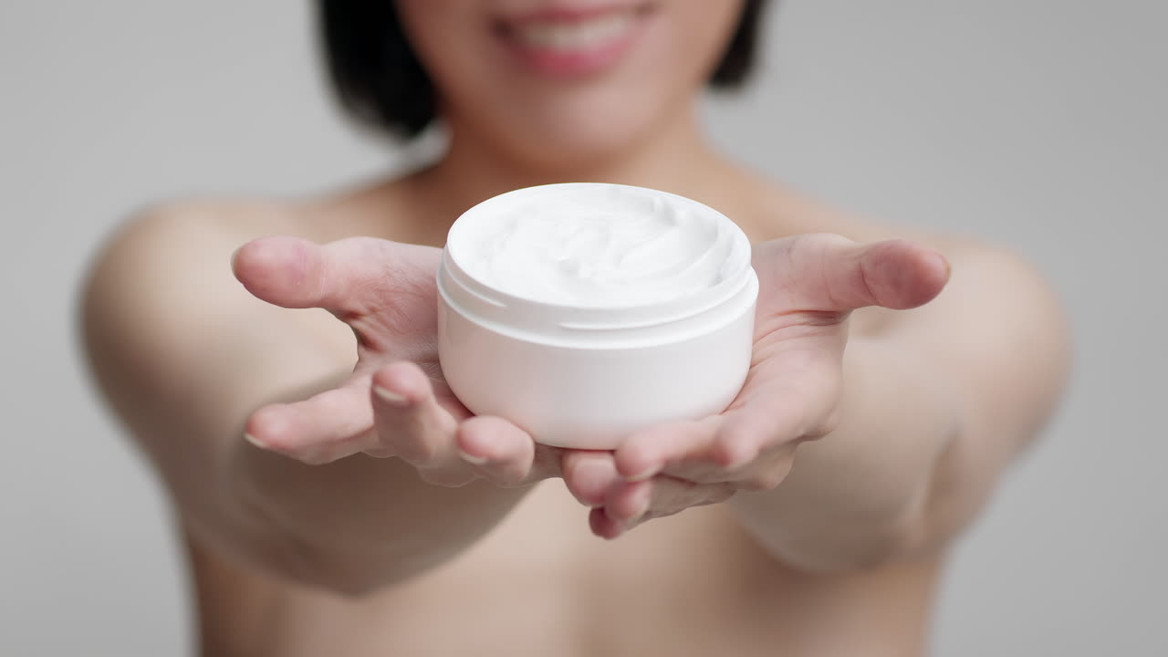 mujer sosteniendo un frasco de crema