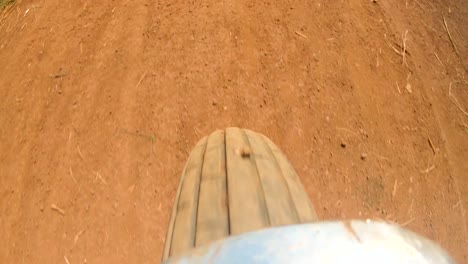 una toma de acción de una rueda de moto que gira rápido mientras acelera a lo largo de un camino rural de tierra