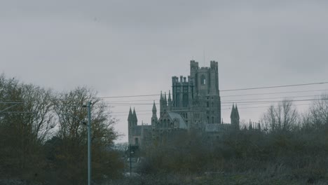 shot of ely cathedral in cambridgeshire, uk standing tall with its turrets in the distance over the tracks on a cloudy day