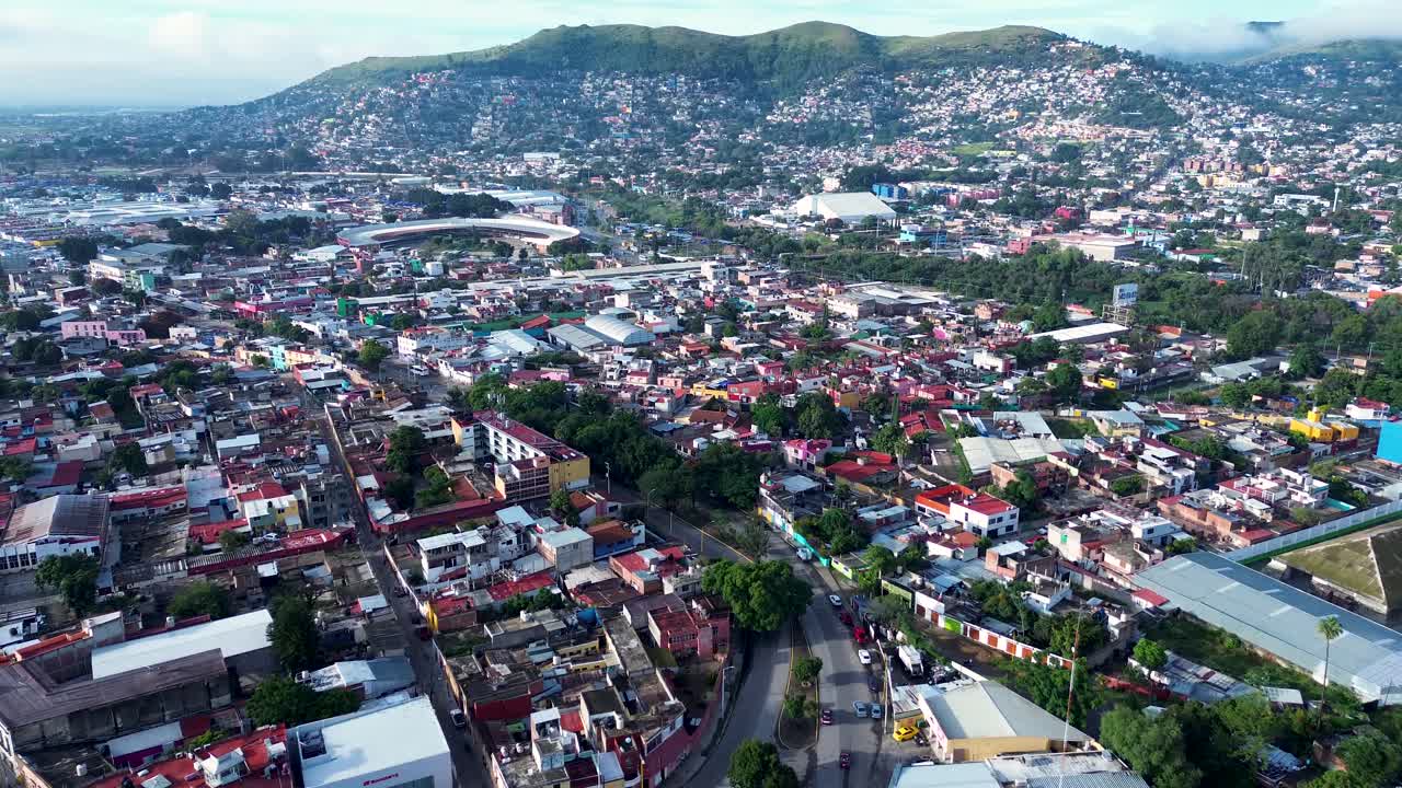 Drone aerial landscape of cars driving along busy city roads streets in neighbourhood suburbs of Oaxaca city Mexico mountain hills housing restaurants shops downtown