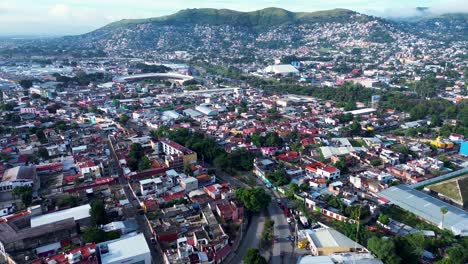 drone aerial landscape of cars driving along busy city roads streets in neighbourhood suburbs of oaxaca city mexico mountain hills housing restaurants shops downtown
