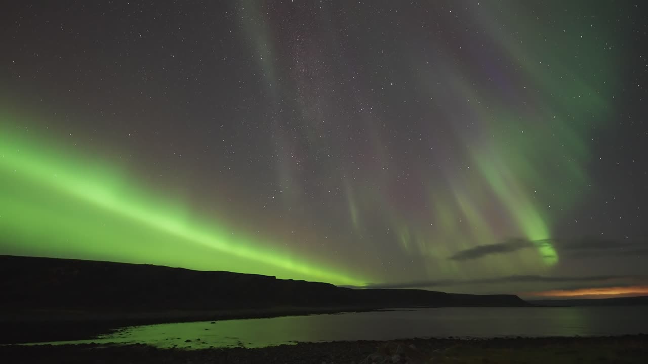la hermosa danza de la aurora boreal en el cielo de invierno ilumina las oscuras aguas tranquilas del fiordo.