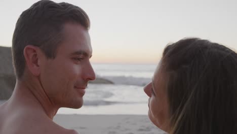 una joven pareja de adultos relajándose en la orilla del mar