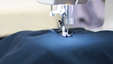 fotografía de cerca de una máquina de coser que está cosiendo un patrón de zigzag en una tela azul usando hilo blanco