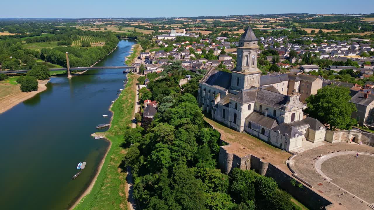 Aerial of Abbey Church Saint Florent, river and Loire Valley landscape in background, panoramic pullback midday